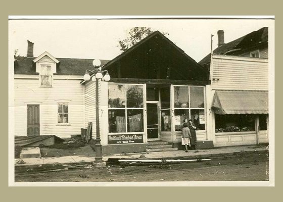 People standing in front of Cooper's grocery store, which is missing part of roof