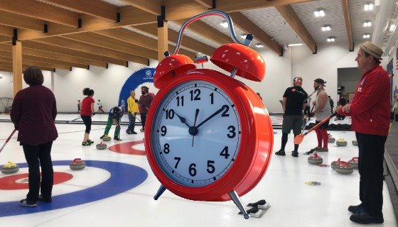 A big alarm clock in the middle of a people curling