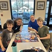 image of a family smiling while doing a puzzle